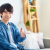 自宅でグッドサインを出す男性