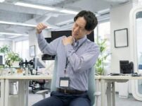 デスクワークで肩こりに悩む男性