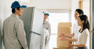 家電を家に搬入する作業員とそれを喜ぶ家主